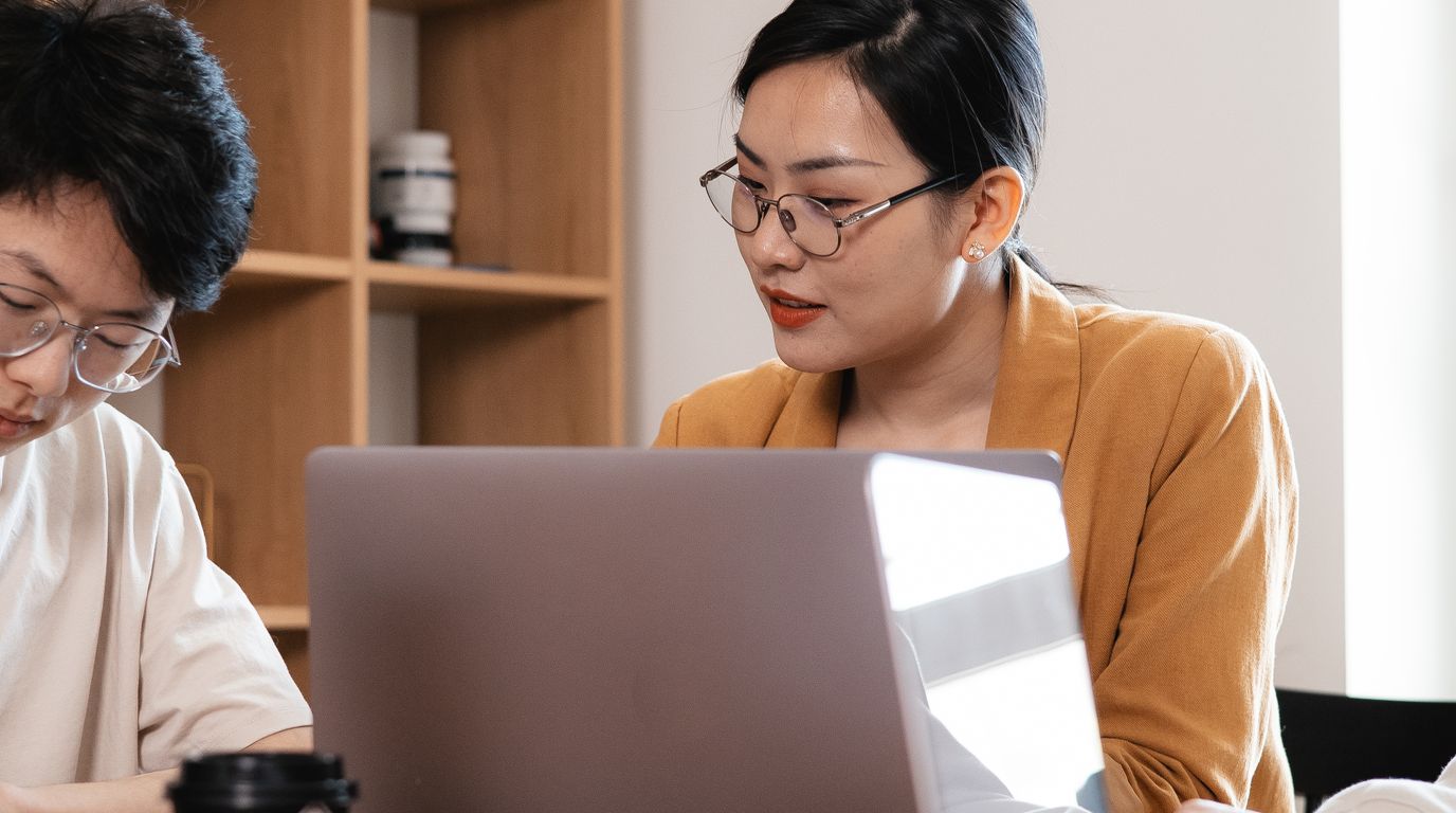 Dua rekan kerja belajar bersama di depan laptop